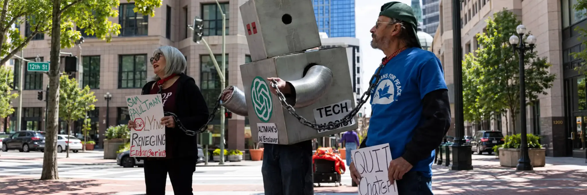 Protesters in a city holding a robot figure in chains and signs questioning AI control